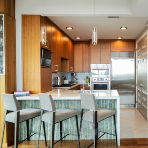 Junior Penthouse kitchen showcasing a stunning water-cut Italian marble facade on the peninsula, custom-designed barstools, Palmer Todd cabinetry, stainless steel Thermador appliances, and a quartzite backsplash seamlessly extending up the wall, located in the Alteza.