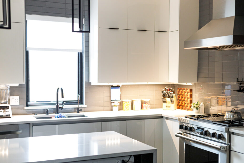 Contemporary kitchen showcasing European cabinetry, polished quartz countertops, and a Wolf range beneath a sleek stainless steel hood.